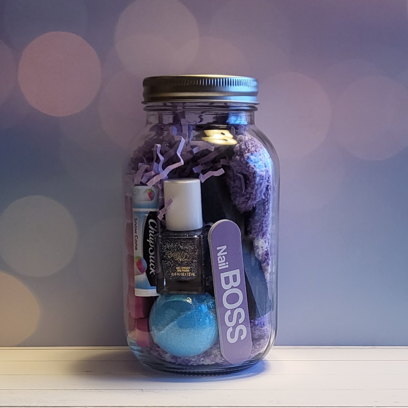 A 32oz mason jar packed with some pedicure essentials like a pair of plush socks, nail polish, toe separators, nail file and a bath bomb.
